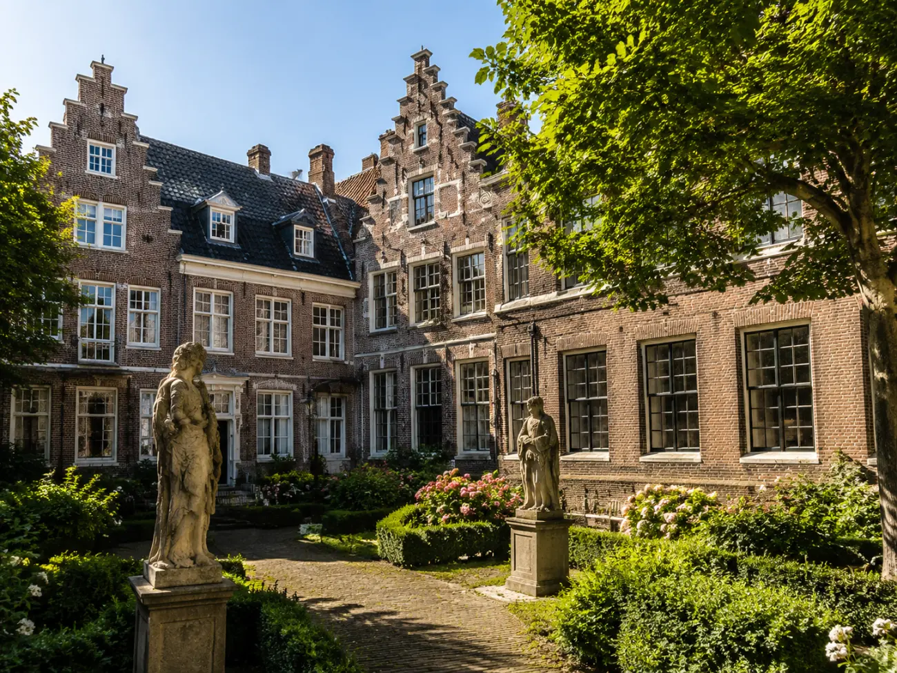Bir Haarlem hofjesinin iç avlusu, heykeller ve çiçekli bahçesiyle
