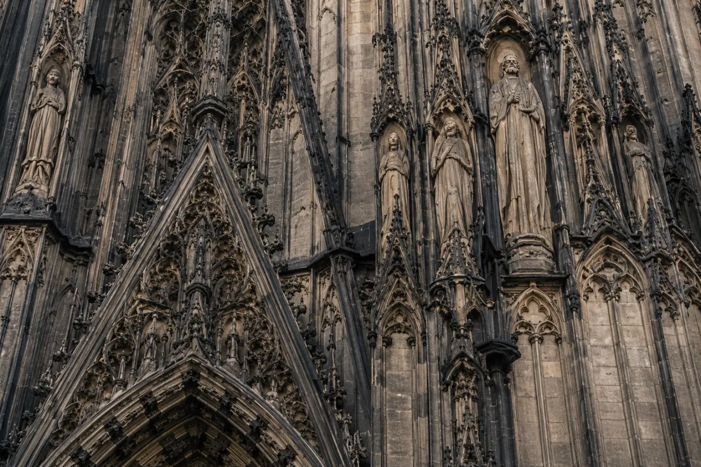 Köln Katedrali batı cephesinin gotik taş işçiliği ve azizler heykelleri yakın plan